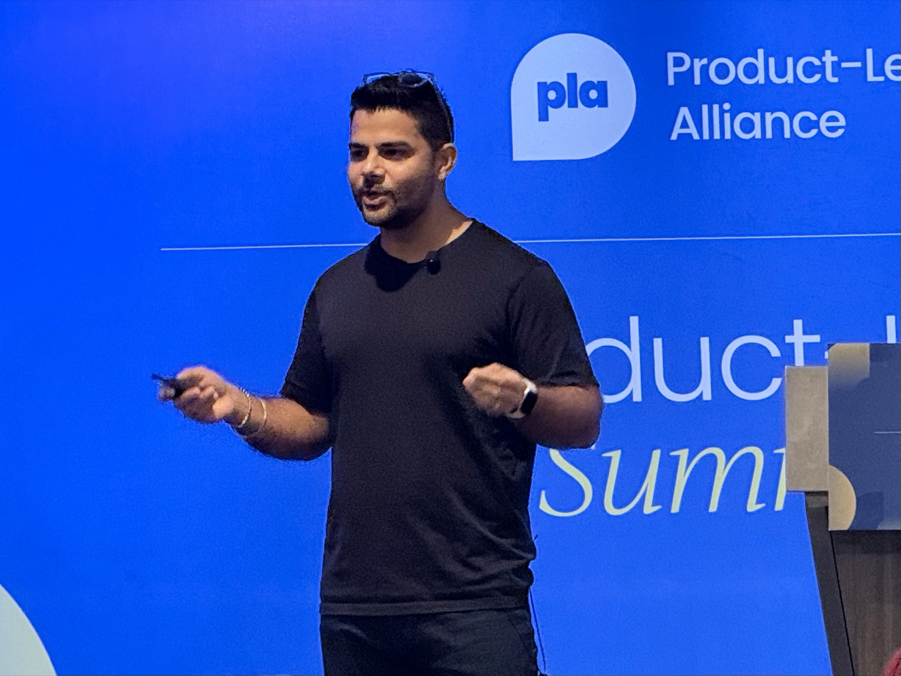 Aakash Pathak giving a presentation on stage at a Product-Led Alliance event